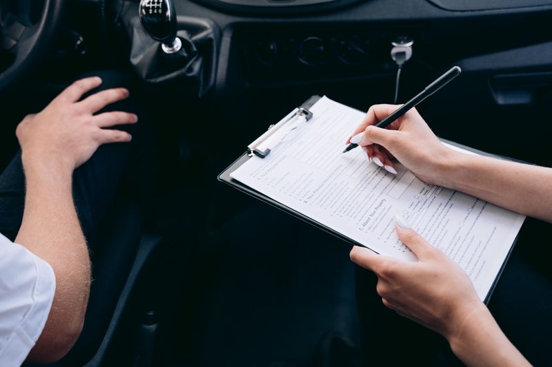 Person writing contract inside vehicle - Auto Insurance